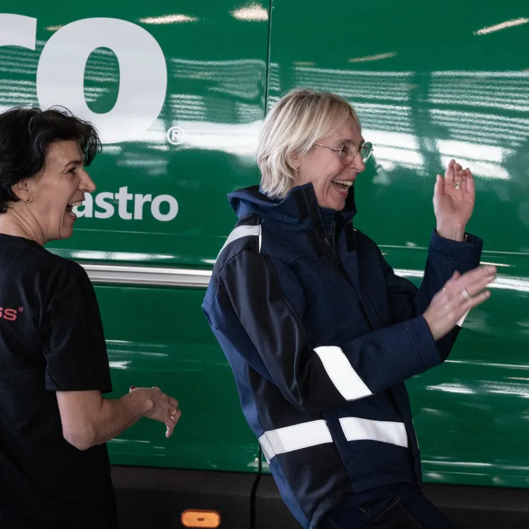 teamdress mitarbeiterin lacht und steht vor einem Alsco Wagen